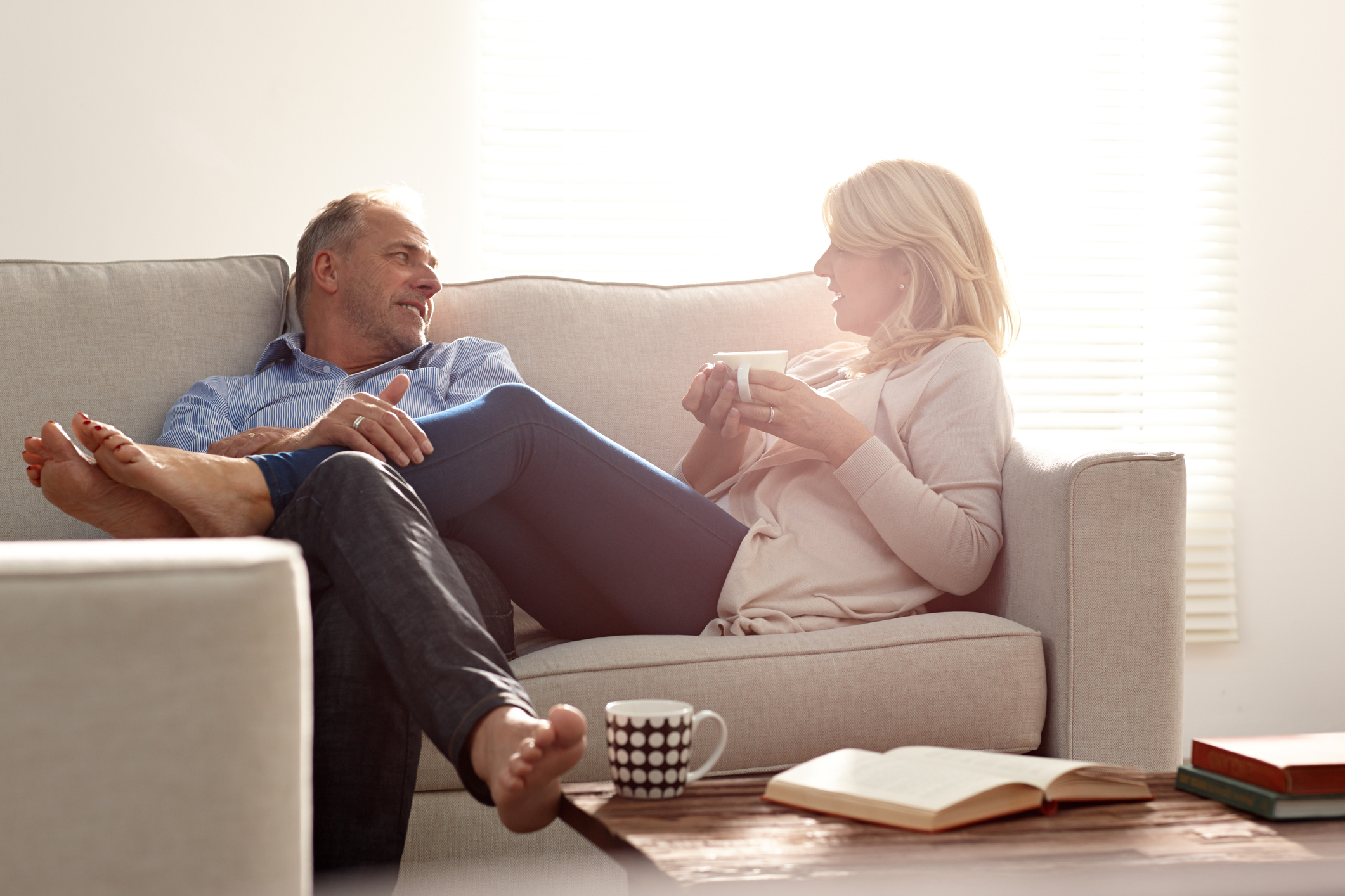 Smiling mature man and woman sitting together on sofa talking in living