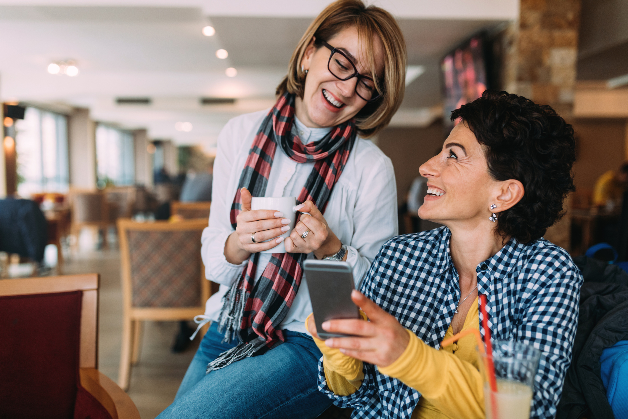 Smiling women in coffee shop with phone