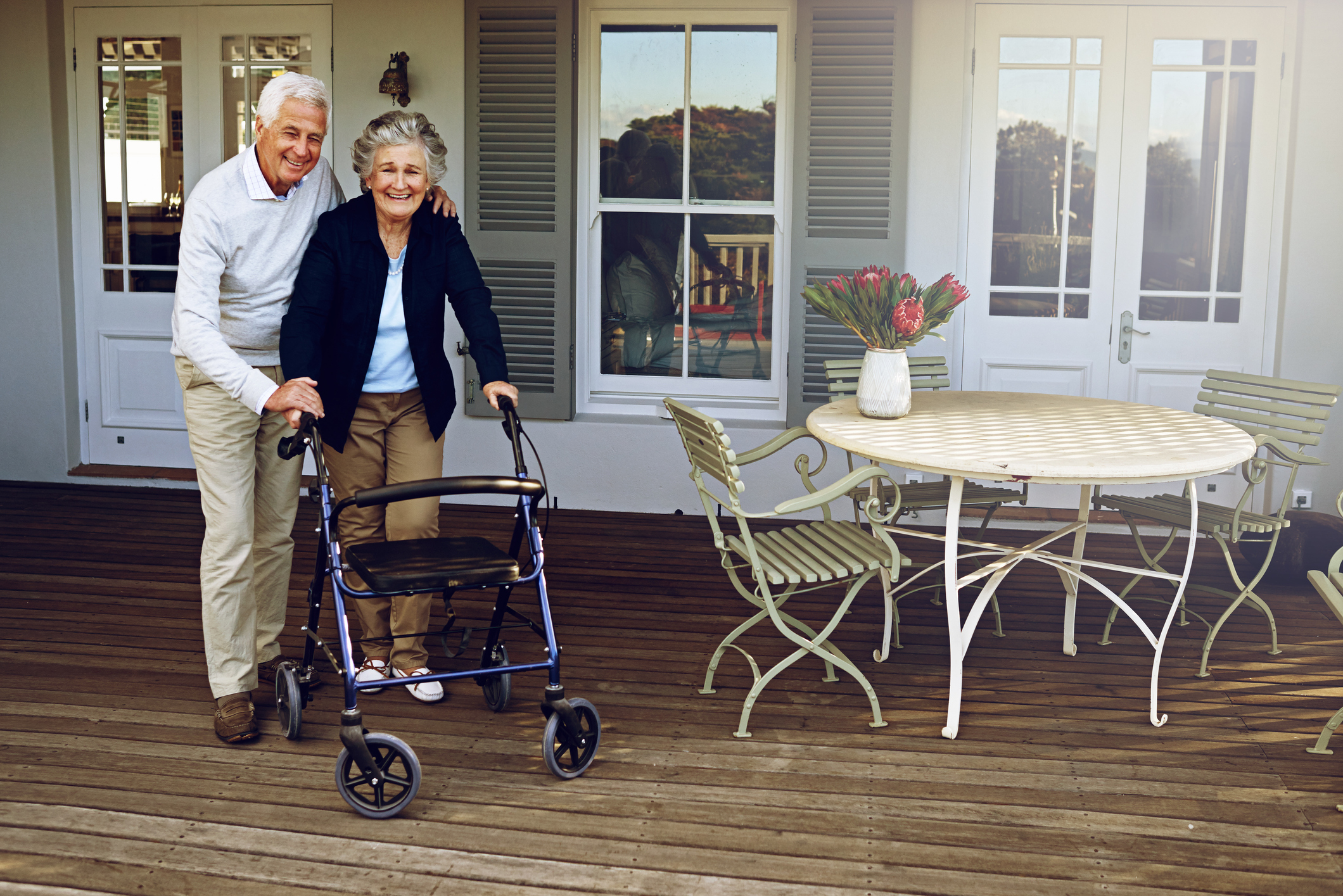 Portrait of a smiling senior woman using a walker with her husband beside her outside their home