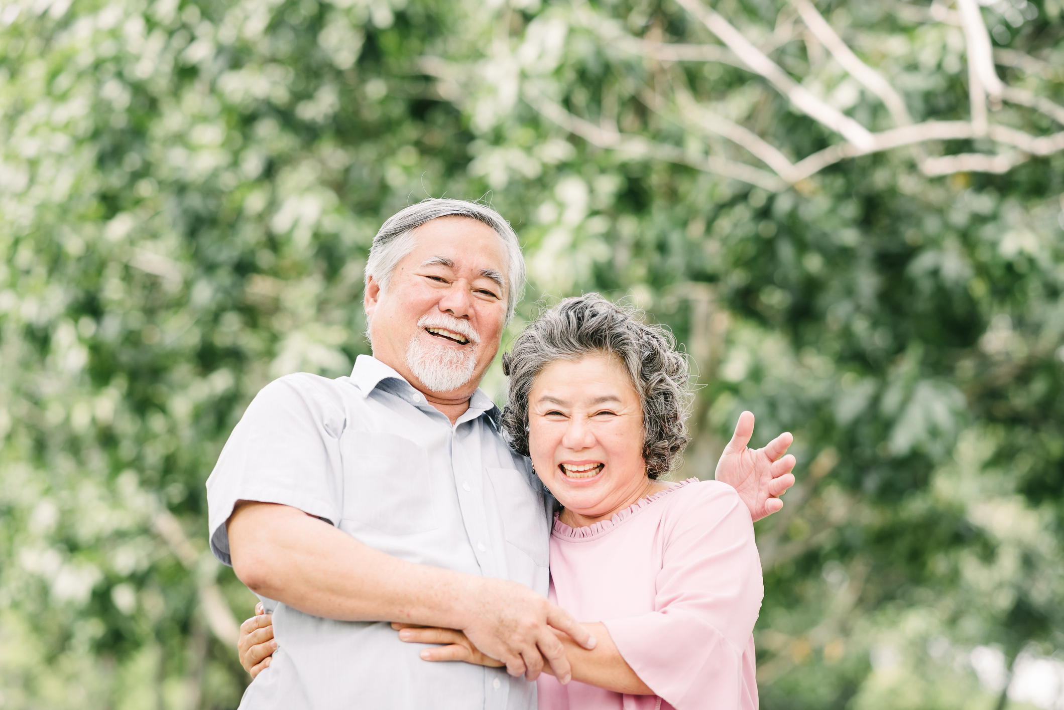 Happy Asian senior couple having a good time. They laughing and smiling while holding each other outdoor in the park.