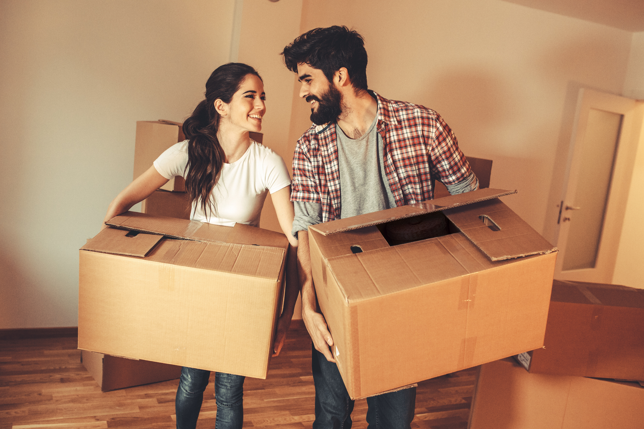 Young couple carrying big cardboard into a new home.Moving house.Real estate concept.