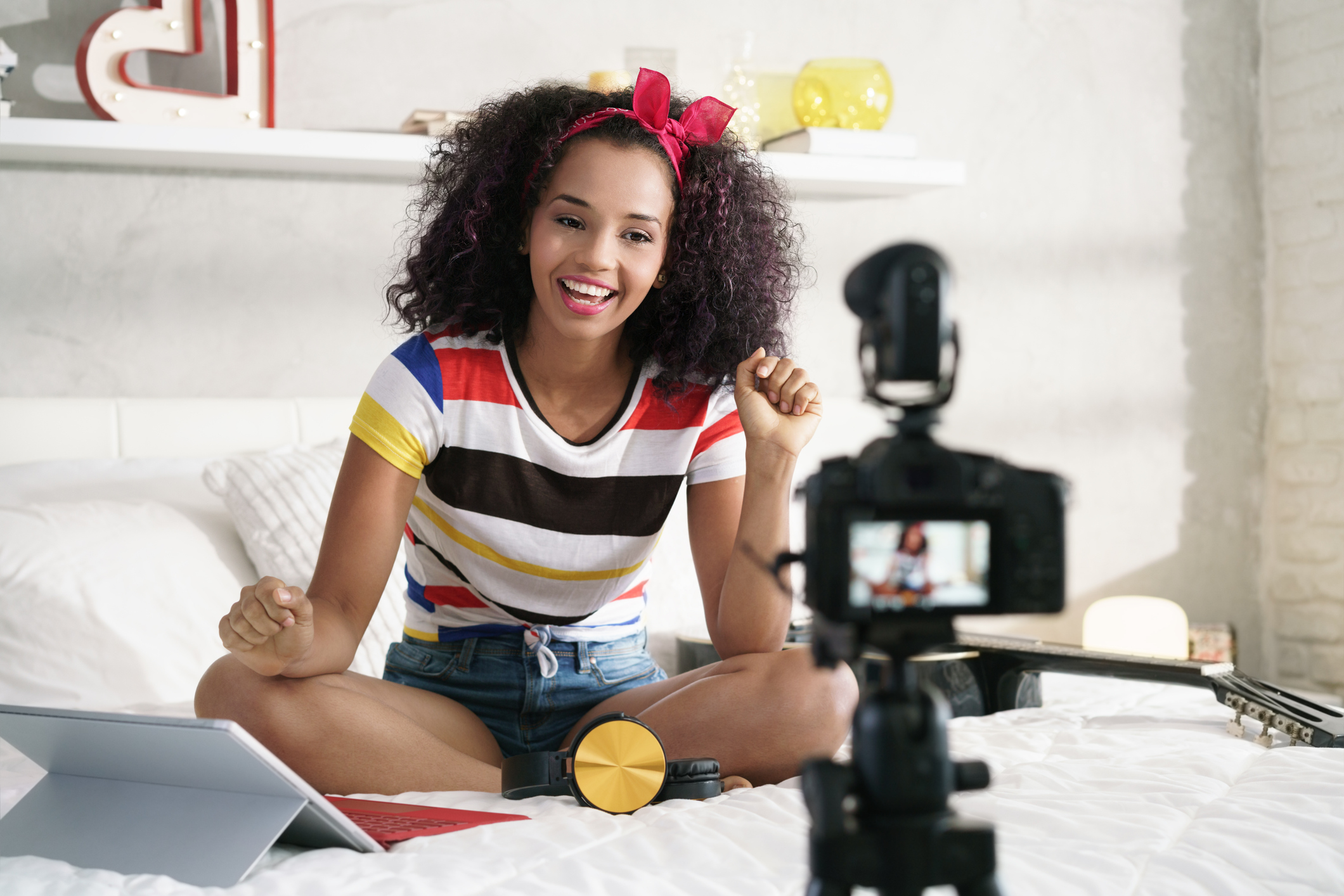 Happy girl at home speaking in front of camera for vlog. Young black woman working as blogger, recording video tutorial for Instagram, Facebook and Internet