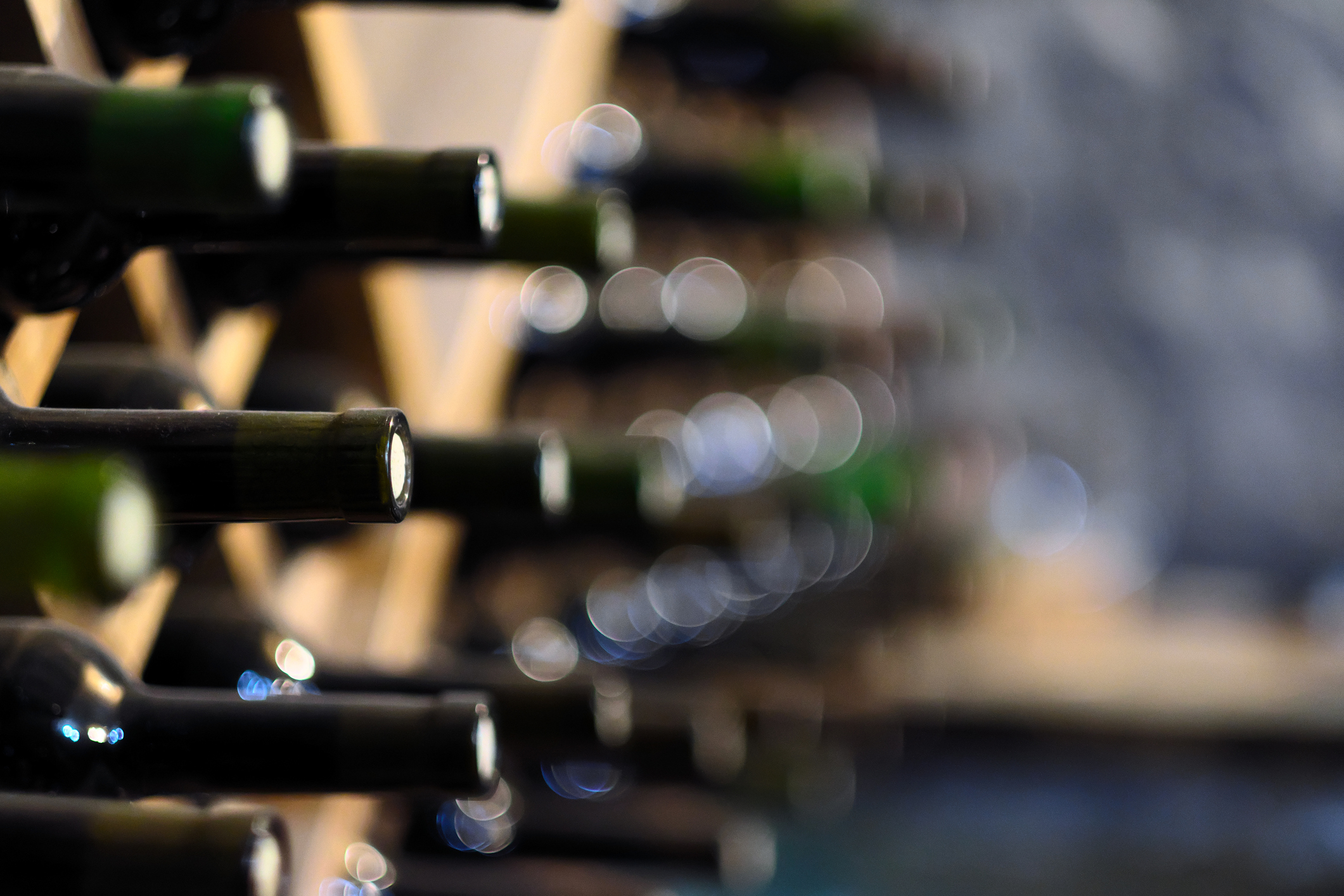 Resting wine bottles stacked on wooden racks in cellar