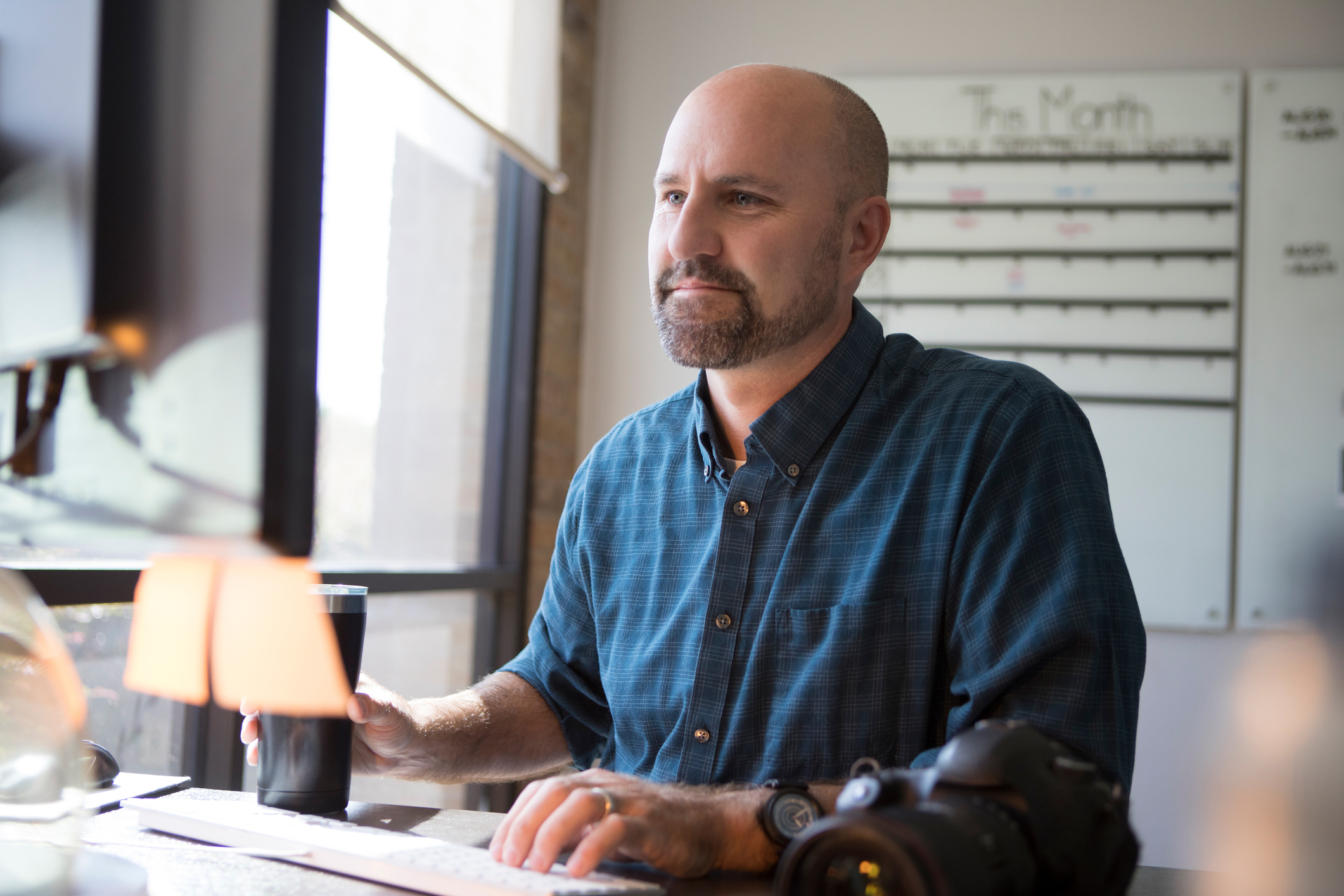 Mid adult Caucasian male photographer concentrates while using a desktop computer to review photos.