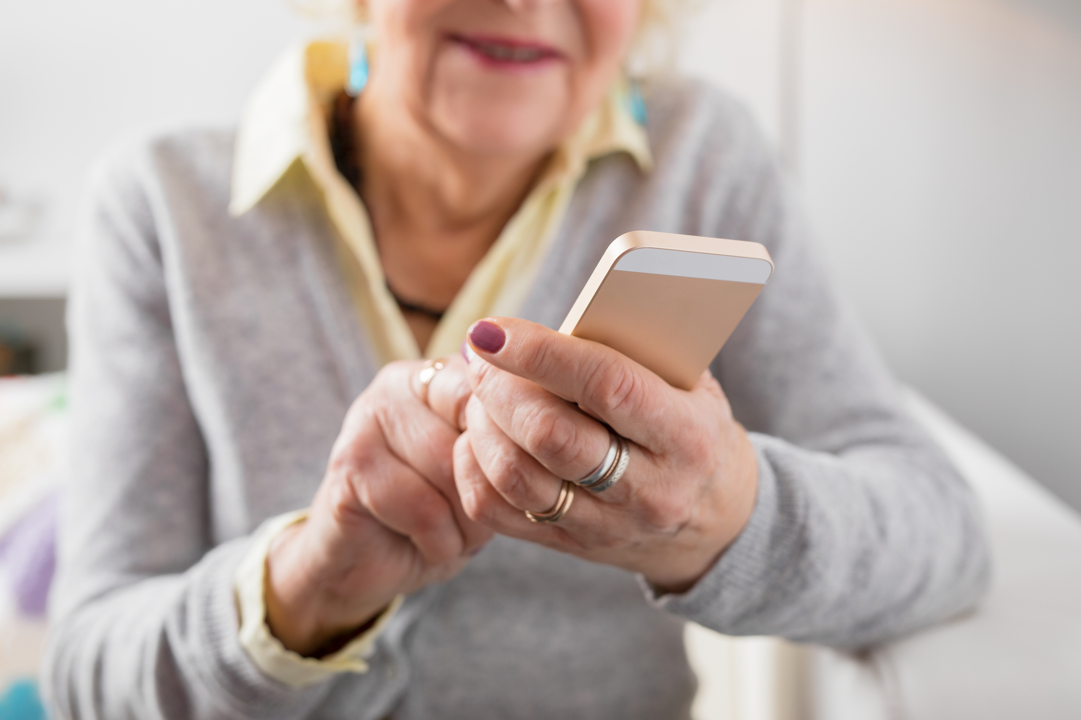 Senior woman holding smartphone in hands and exploring new technology