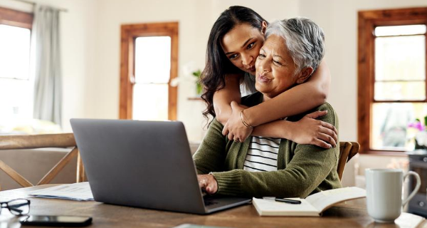 Senior and family member research potential senior living community on a laptop.