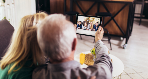 Two seniors video chat on tablet with family members.