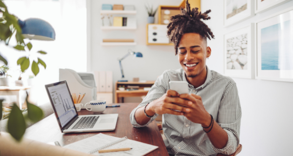 Person on a computer and mobile device with data on computer screen.