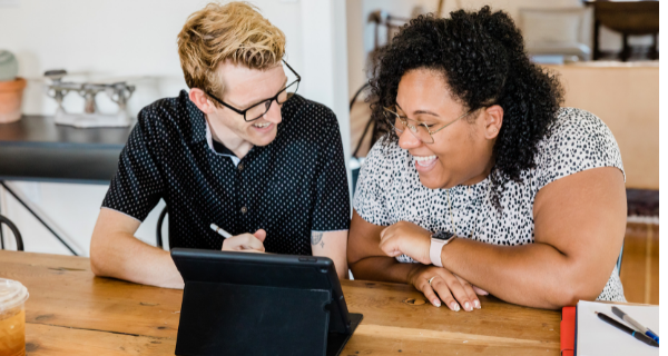 image of two people looking at a computer screen and laughing