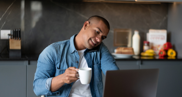 Image of a person drinking coffee, making a phone call, and looking at websites on the computer.