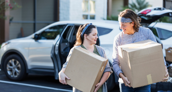 two people carrying boxes from their car to their storage unit.