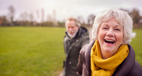 Two seniors walking outside in a park.