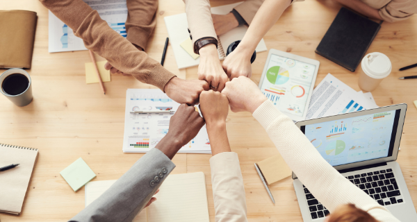 image of marketers fist bumping over a table.